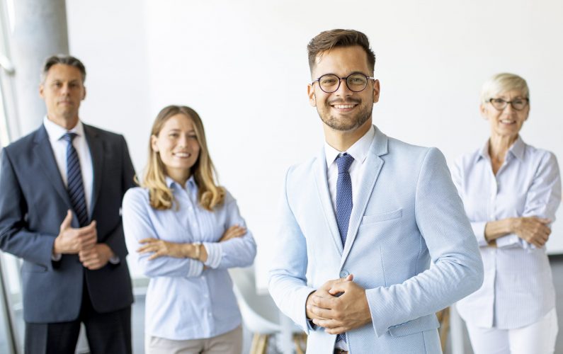 Group of a businesspeople standing together in the office with their young bussines leader