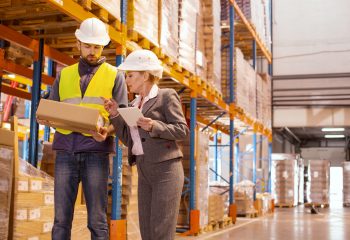 Delivery company. Smart nice woman standing near her subordinate while talking to him