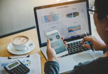 Businessmen use smartphones and laptop to connect and find information in office